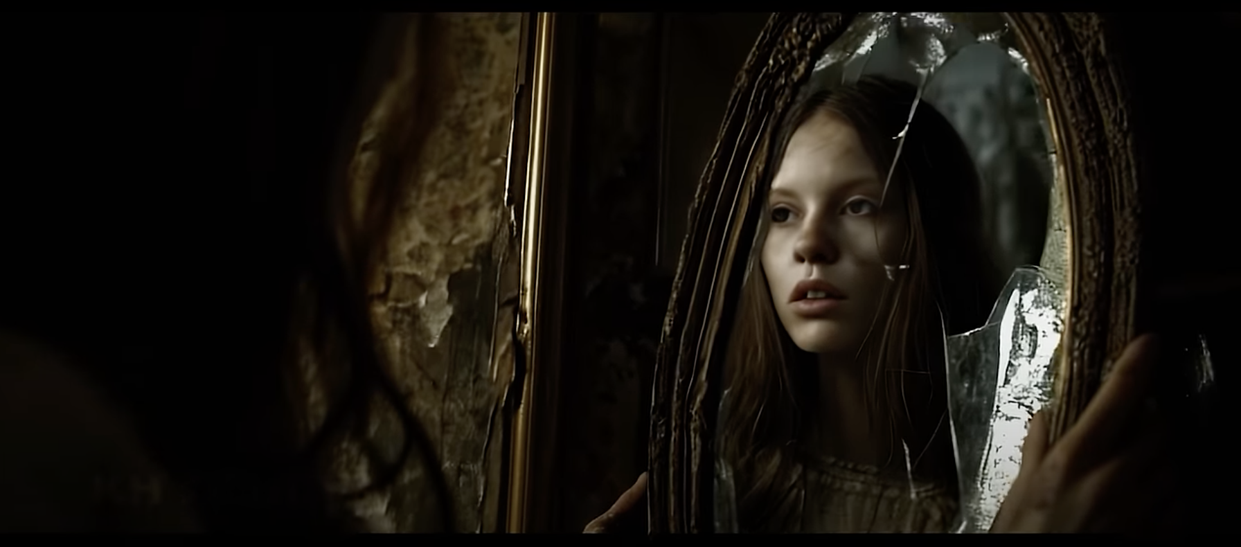 film still showing a girl looking into a broken mirror