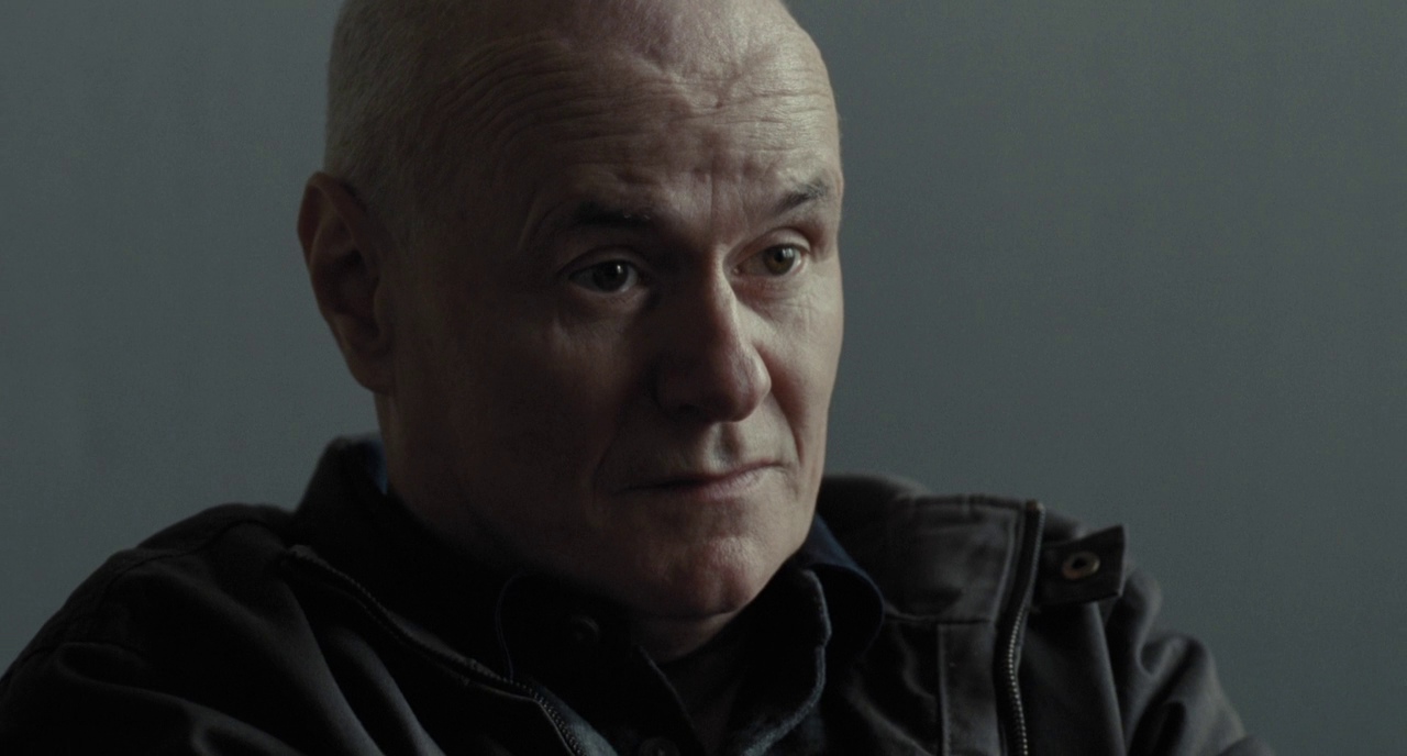 Film still from I, Daniel Blake (2016) showing bald man staring into space by British director Ken Loach
