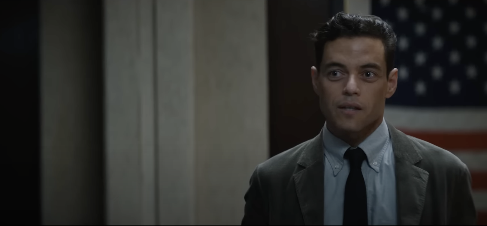 film still from The Amateur showing Rami Malik in front of an American flag